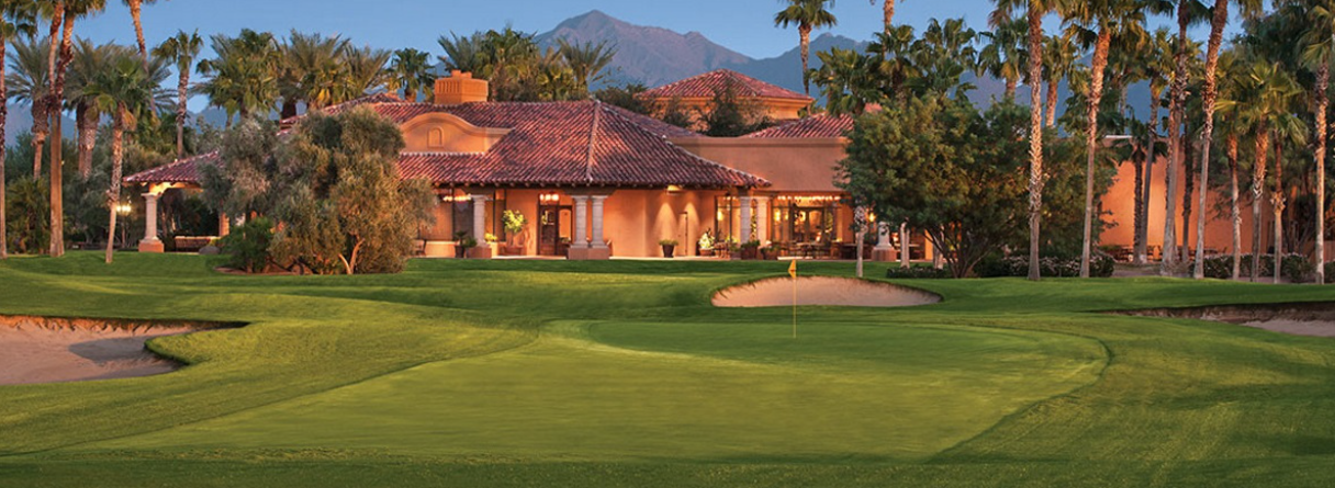 Elegant clubhouse with red tile roof overlooking a manicured green golf course and desert mountains at PebbleCreek in Goodyear, Arizona