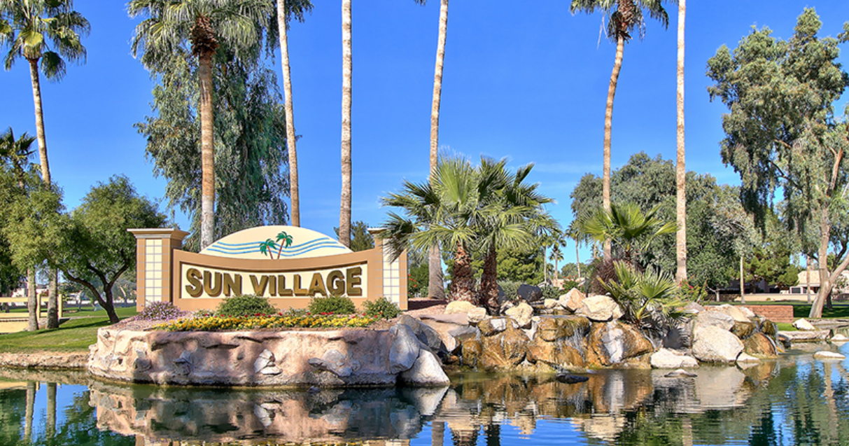 Sun Village entry monument with a waterfall reflecting pond, palm trees and bright blue sky in Surprise, Arizona