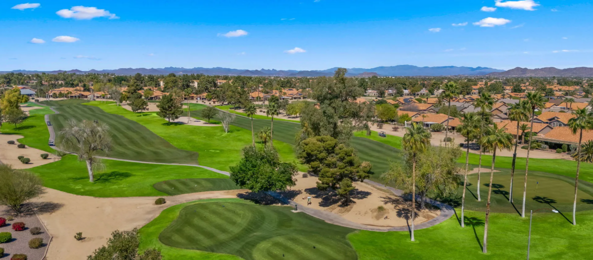 Aerial view of Westbrook Village golf fairways, homes with red tile roofs and distant mountains in Peoria, Arizona